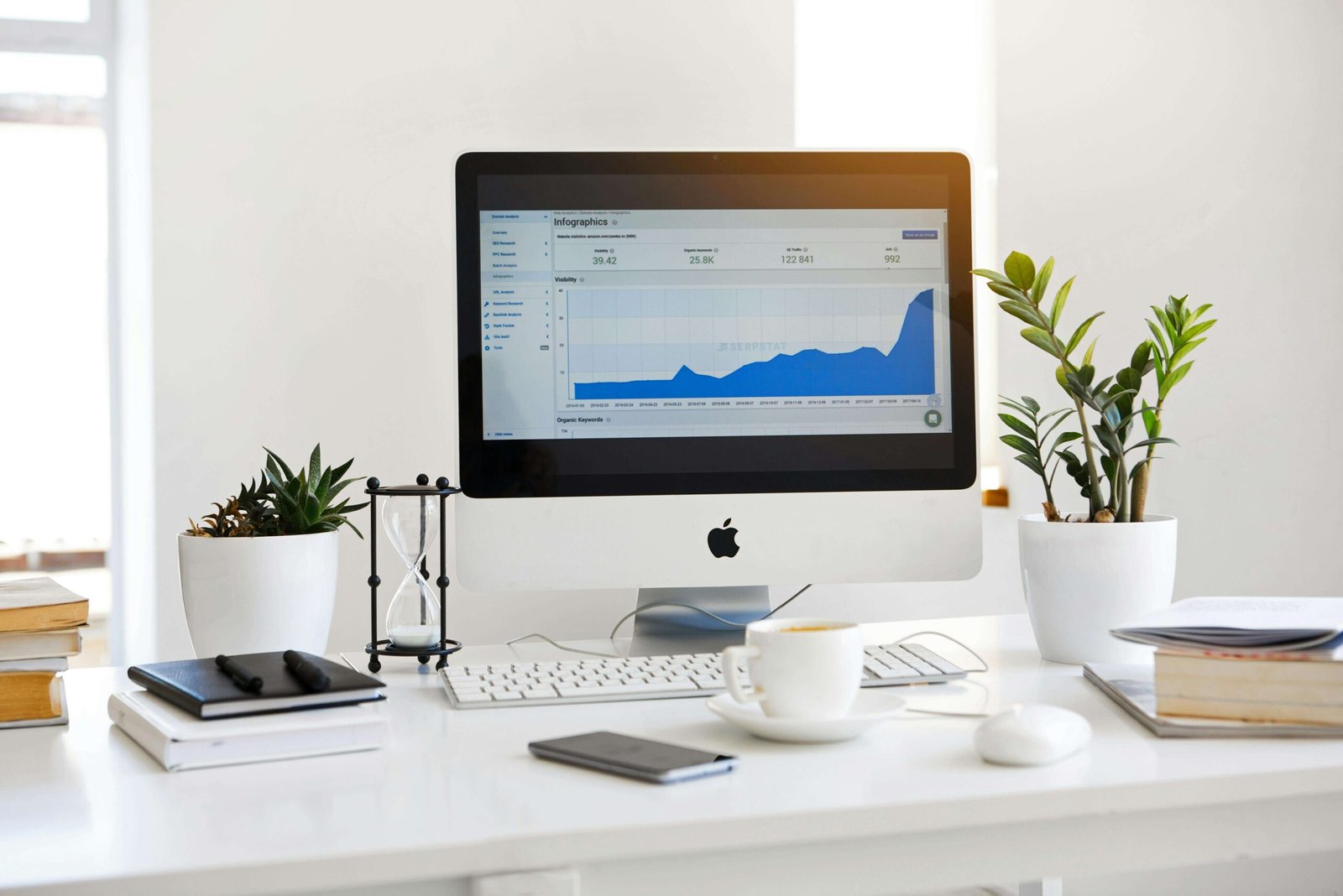 Computer displaying website analytics and growth chart on a clean white desk.